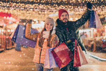 Black friday. Photo of two people students friends raise buy shopping bags under outside x-mas christmas time evening illumination