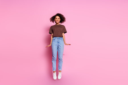 Full length photo of lovely young lady girlish jumping dressed stylish brown garment isolated on pink color backgroundの写真素材