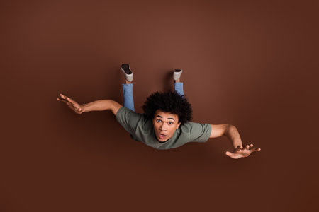 Full size photo of nice young guy falling down nervous wear trendy khaki outfit isolated on brown...