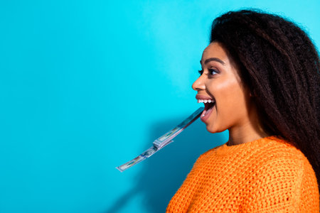 Photo portrait of lovely young lady catch money open mouth dressed stylish knitted orange garment isolated on blue color backgroundの写真素材