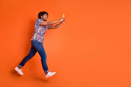 Full body photo of attractive young man hold device running dressed stylish colorful clothes...