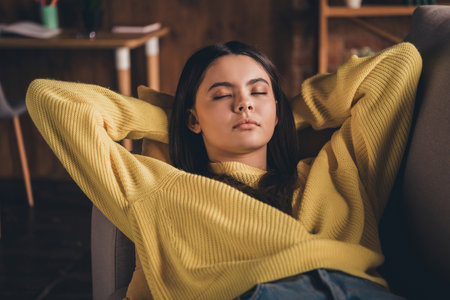 Photo portrait of nice teen lady lying sofa sleeping closed eyes dressed yellow garment spend pastime spacious house indoors roomの写真素材