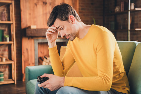 Photo portrait of young guy sit couch lose video game upset dressed yellow garment spend pastime...