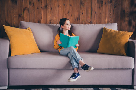 Photo of pretty cheerful little lady wear yellow pullover sitting couch smiling enjoying fairytale indoors room home houseの写真素材
