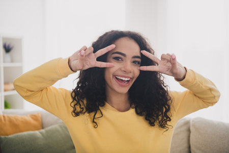 Photo portrait of cheerful young girl wearing yellow shirt optimistic posing double peace symbol v...