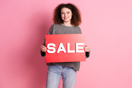 Photo portrait of lovely young lady hold sale plate banner dressed stylish gray garment isolated on...