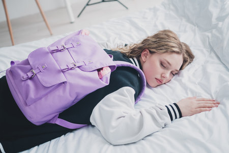 Portrait of sweet cute teen lady lying bed tired wear trendy school uniform prepare bedroom light...