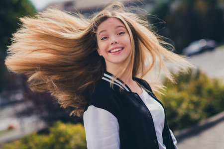 Photo portrait of pretty teenager girl fluttering hair excited smile wear trendy uniform outfit walk outside green park backgroundの写真素材