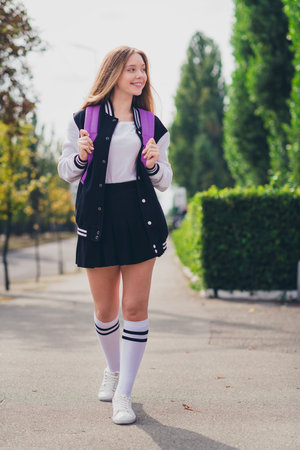 Full size vertical photo of pretty teen girl look empty space dressed stylish uniform outfit walk outside green park backgroundの写真素材
