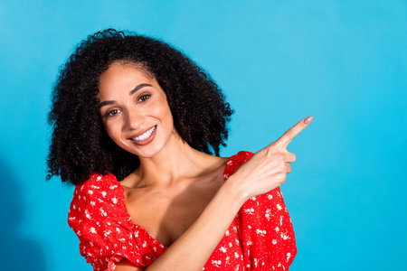 Photo of pretty young woman direct finger empty space wear top isolated on blue color backgroundの写真素材