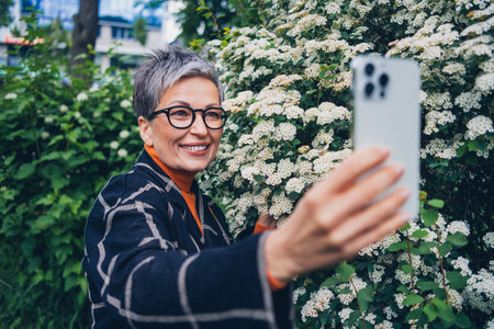 Portrait of nice aged woman smart phone make selfie walk park downtown outdoors