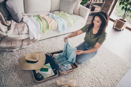 Photo of pretty sweet lady wear khaki t-shirt packing luggage summer trip indoors room home house