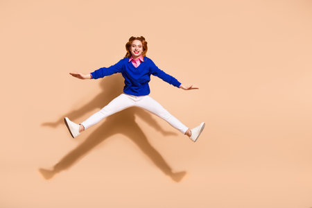 Full size photo of nice young woman jump empty space wear pullover isolated on beige color...