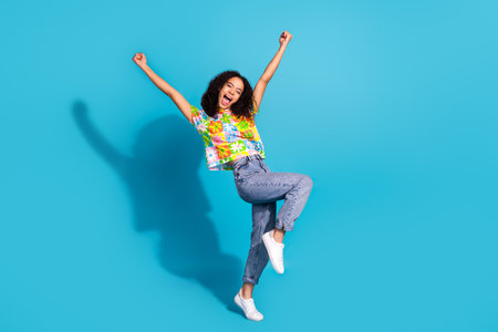 Full length photo of lucky attractive lady dressed flower print t-shirt rising fists empty space isolated blue color backgroundの写真素材