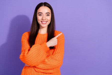 Photo of cute pretty girl wear stylish orange clothes recommend empty space isolated on purple color backgroundの写真素材