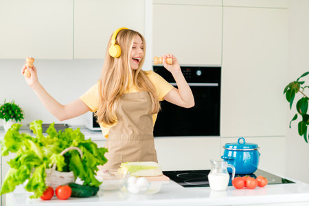 Photo of charming cheerful girl cooking meal preparing soup lunch have fun listen music modern kitchen indoorsの写真素材