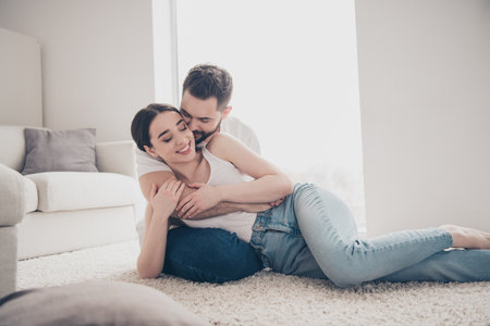 Photo of shiny cute couple dressed casual outfits kissing embracing together enjoying being home indoors house apartment roomの写真素材