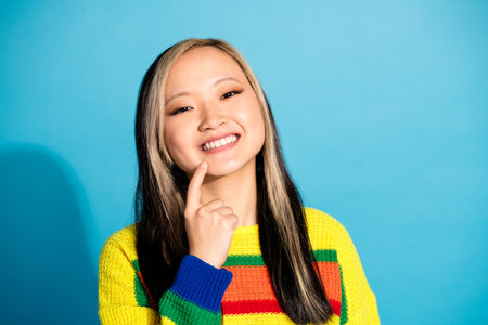 Photo portrait of pretty young girl touch chin thoughtful charming wear trendy striped outfit isolated on blue color backgroundの写真素材
