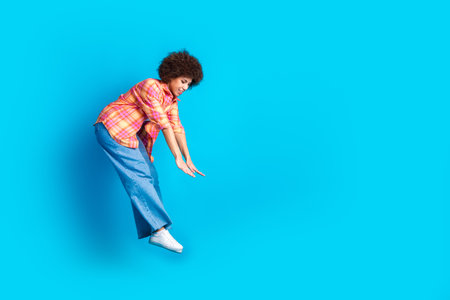 Full body photo of pretty young girl jumping pushing invisible things wear trendy plaid outfit...