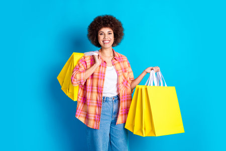 Photo portrait of pretty young girl hold shopping bags wear trendy plaid outfit isolated on blue...