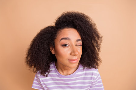 Photo of nice young woman eye look watch wear striped t-shirt isolated on beige color backgroundの写真素材