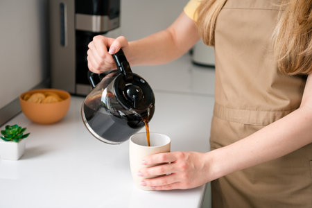 Cropped photo of nice teen girl pour coffee machine device wear apron cooking tasty meal recipe kitchen indoorsの写真素材