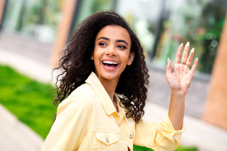 Portrait of lovely nice young girl smile arm wave hi walk city street outdoorsの写真素材