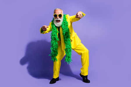 Full body portrait of funny extravagant aged man point fingers you yellow suit isolated on purple...
