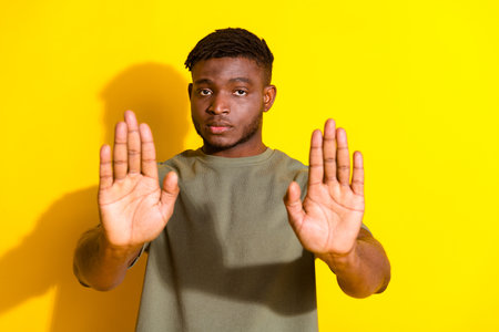 Photo of handsome nice man wear khaki stylish clothes stop sign isolated on yellow color backgroundの写真素材