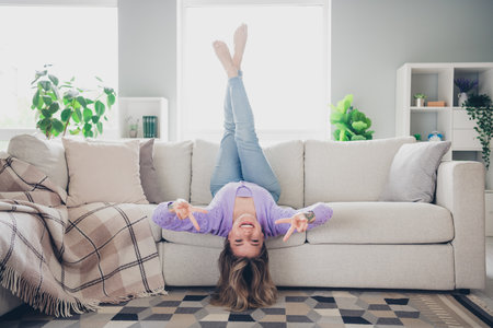 Full size photo of attractive young woman lying couch upside down have fun dressed purple outfit...