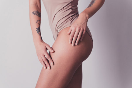 Cropped photo of pretty young girl model posing touch hips legs no filter dressed stylish gray underwear isolated on studio backgroundの写真素材