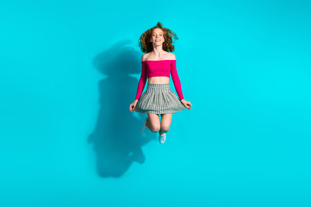 Full size photo of pretty young girl jump wear top isolated on teal color backgroundの写真素材