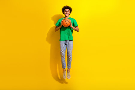 Full length photo of funky cool guy dressed green t-shirt jumping high rising ball emtpy space...