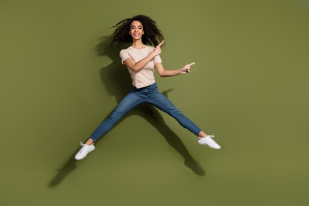 Full size photo of positive girl dressed beige t-shirt jeans fly directing at discount empty space...