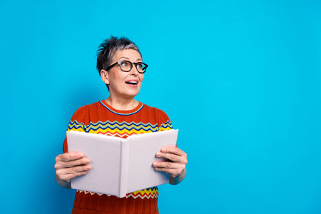 Photo of nice aged woman book look empty space wear t-shirt isolated on blue color background