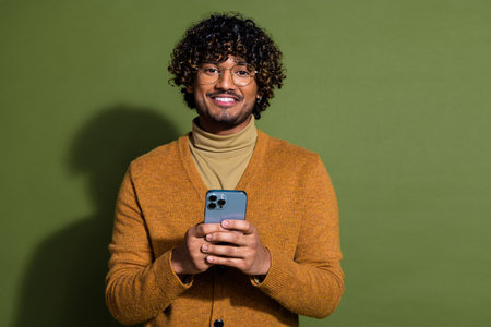 Photo portrait of attractive young man hold device dressed stylish brown clothes isolated on khaki...