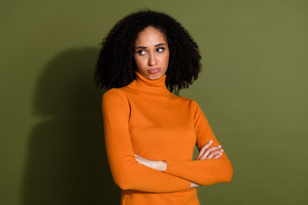 Photo of bored unhappy girl wear orange jumper arms folded looking empty space isolated khaki color backgroundの写真素材