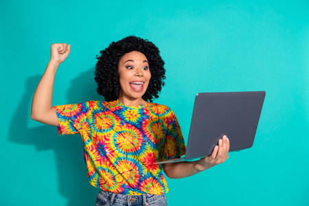 Photo of adorable lucky girl wear print t-shirt winning game modern device empty space isolated turquoise color backgroundの写真素材