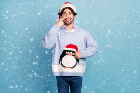 Photo of charming happy positive man point finger nose christmas mood isolated on blue color backgroundの写真素材
