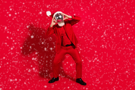 Photo of funky funny age gentleman wear new year costume headwear dancing disco ball close face isolated red color backgroundの写真素材