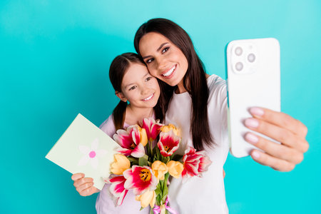 Photo of adorable cute nice girl taking selfie picture 8 march isolated on cyan color backgroundの写真素材