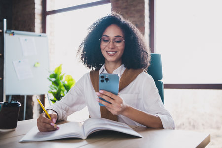 Portrait of elegant corporate worker lady hold pencil phone wear white shirt business center indoorsの写真素材