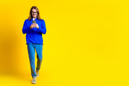 Photo of glad funny handsome man wear trendy blue clothes go empty space isolated on yellow color backgroundの写真素材
