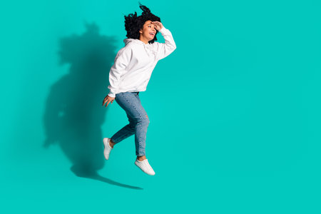 Photo portrait of young funny chevelure hairstyle lady wearing white hoodie looking far away jumping isolated on aquamarine color backgroundの写真素材