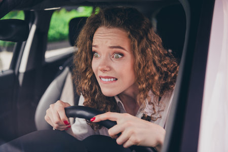 Photo of shocked pretty lady dressed white shirt smiling driving rented automobile outdoors urban city streetの写真素材