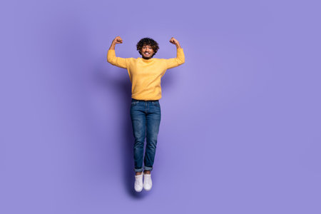 Photo of cheerful funky nice strong man wear trendy yellow clothes jump up isolated on purple color backgroundの写真素材
