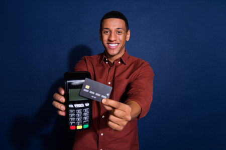 Photo of funky excited guy dressed brown shirt showing bank card terminal isolated blue color...