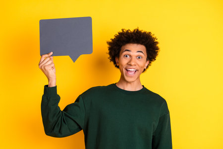 Portrait of nice young man hold empty space dialogue bubble wear sweater isolated on yellow color backgroundの写真素材