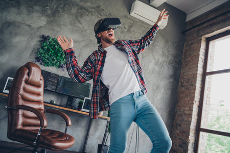 Photo of entertainment in loft modern design living room young carefree guy wearing virtual reality...