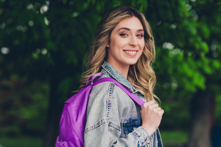 Profile portrait of pretty young girl carry backpack beaming smile wear denim jacket walk street outdoorsの写真素材